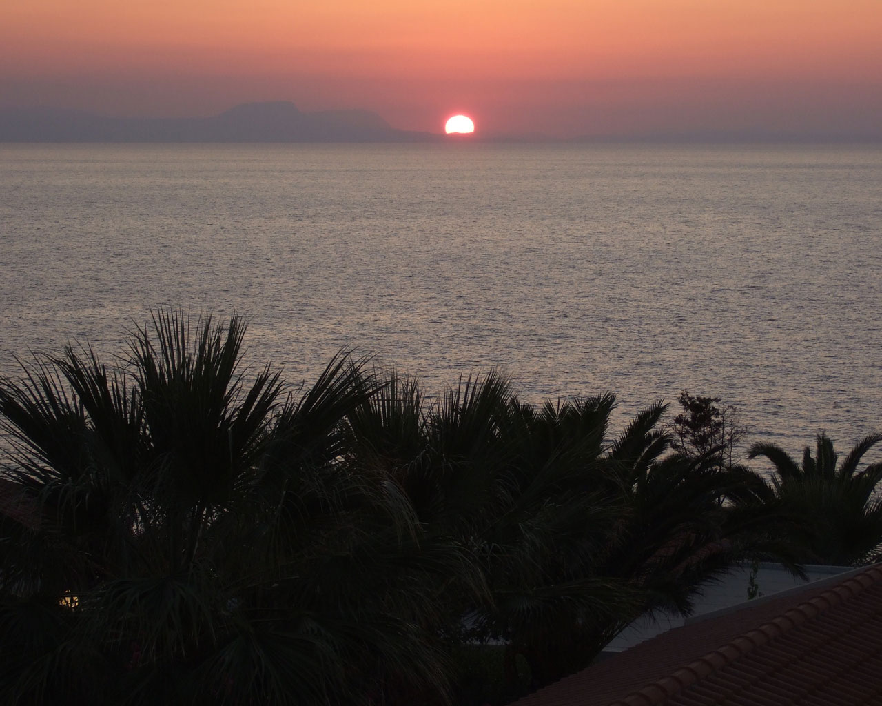 Sun sets in the sea after a far mountain.