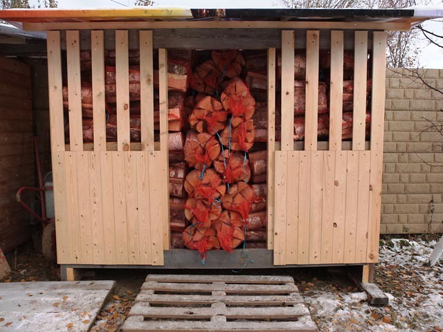 Дровница с берёзовыми дровами в красных сетках